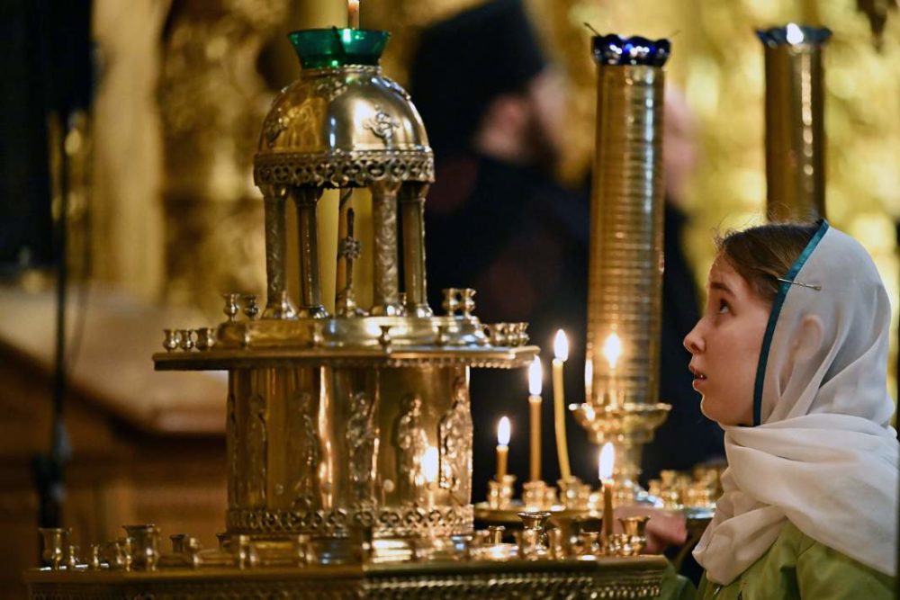 верующая перед свечами риа